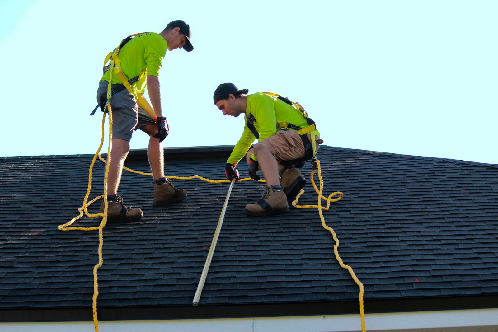 Two roofers measuring a residential shingle roof together